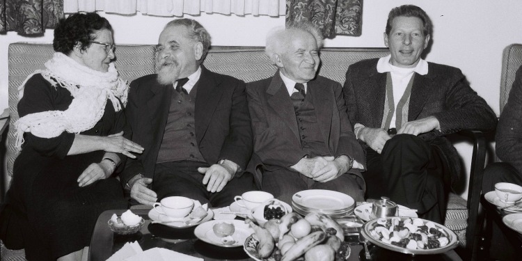 Black and white image of four people sitting together on a couch.