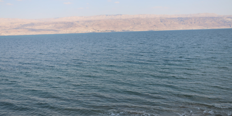 Image of the Dead Sea during a sunny day with mountains behind it.