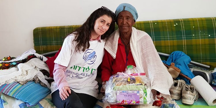 An IFCJ volunteer delivering food to an elderly woman during Purim.