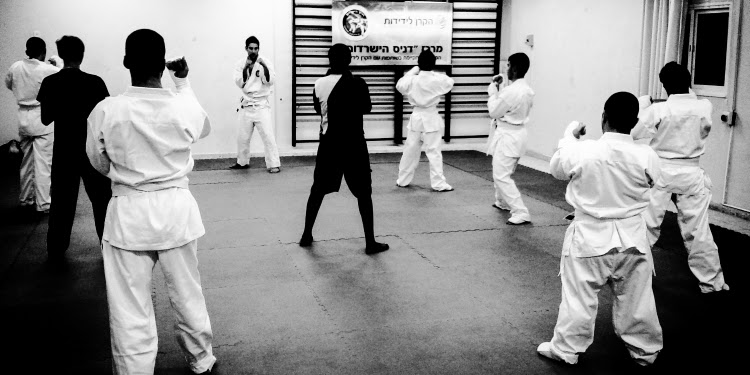 Black and white image of several people in a martial arts class.
