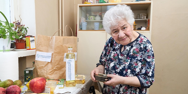 Elderly woman stands unpacking branded food bag