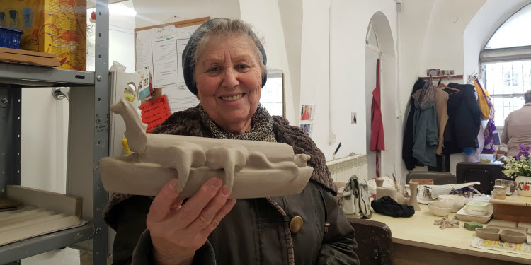 Elderly Jewish woman showing off a sculpture she made.