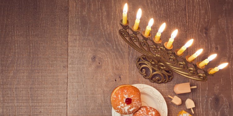 Donuts, dreidels, and a menorah sitting on a wooden table.