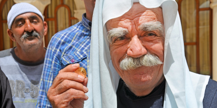 A Druze sheikh holding a gold coin.