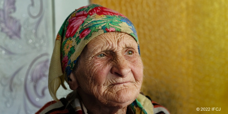 Elderly Jewish woman wearing scarf on her head looking sad