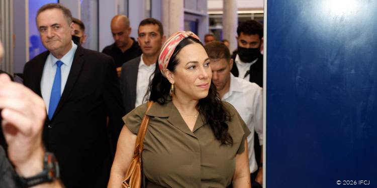 Woman with headscarf in a crowded indoor setting, among focused attendees.