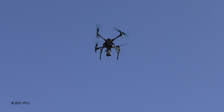 A drone flying in a blue sky for a security demonstration.