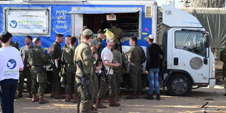 IDF reservists gather around a mobile support truck, receiving supplies and assistance, reflecting gratitude and solidarity from the community.