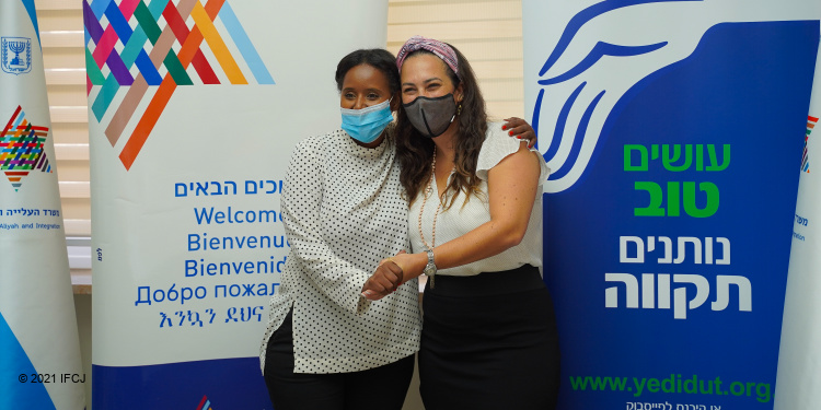 Yael Eckstein and a woman at the Rosh Hashanah Tost with IFCJ banners behind them.