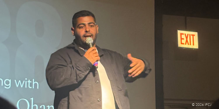 A man speaking passionately at an IFCJ event, engaging with the audience to promote charitable initiatives and community support programs.