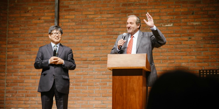 Rabbi Eckstein with a man to his right as he gives a speech at a podium.