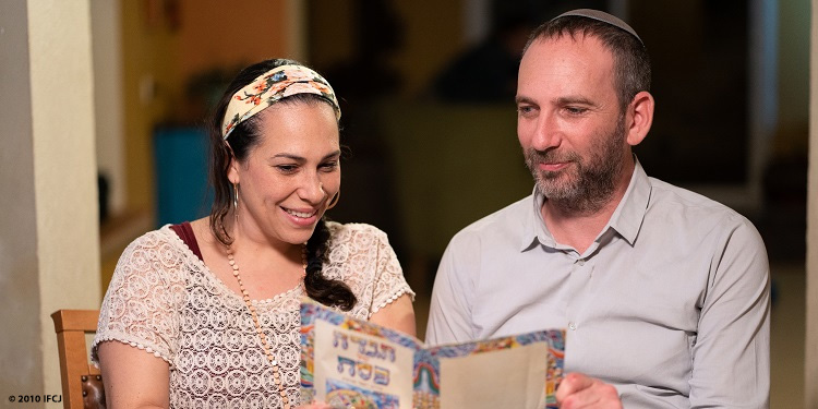 Yael Eckstein and Ami sitting at a table smiling at a book together.