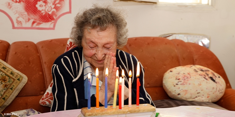 Elderly Jewish woman celebrates Hanukkah with a menorah.