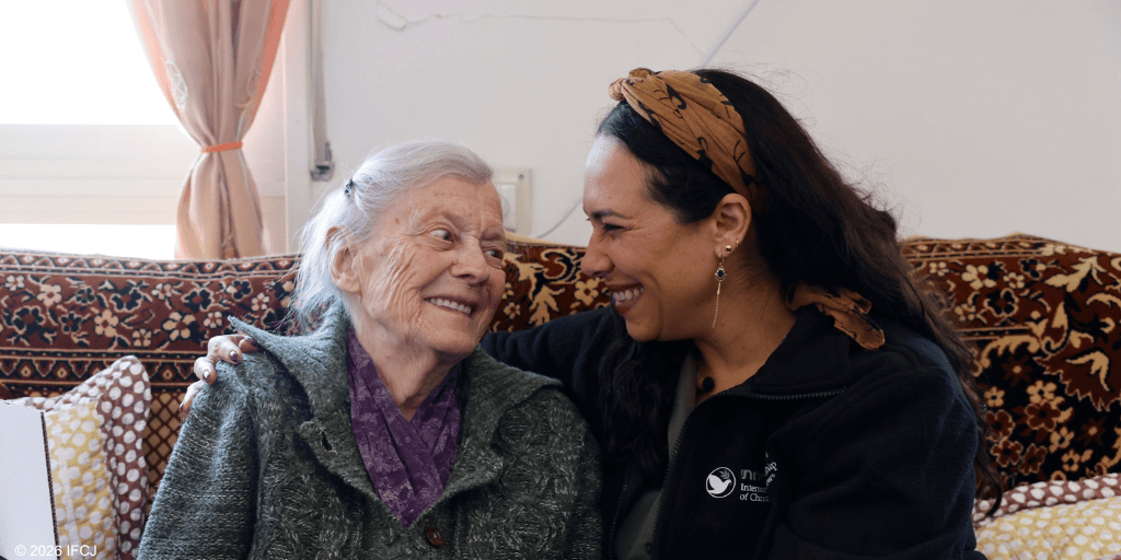 A young woman caring for an elderly woman, sharing a joyful moment at home, highlighting compassion and support for seniors.