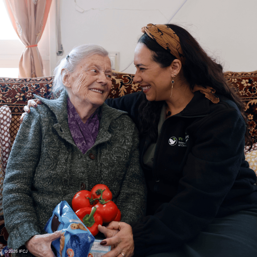 A young woman caring for an elderly woman, sharing a joyful moment at home, highlighting compassion and support for seniors.