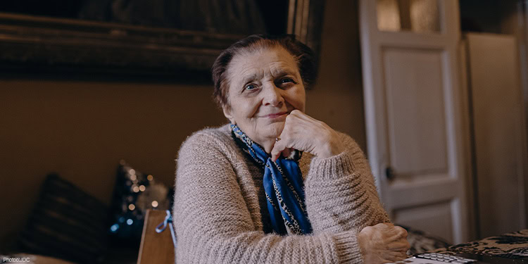 Elderly lady sitting at the table wearing a tan sweater