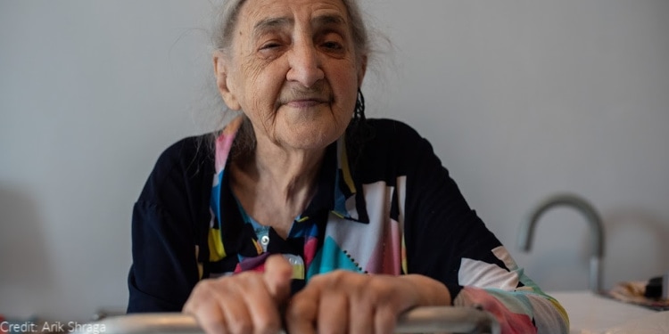 elderly woman, walker, eyes closed, black and multicolored patterned shirt