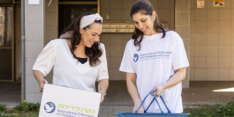 Yael with young woman distributing food boxes