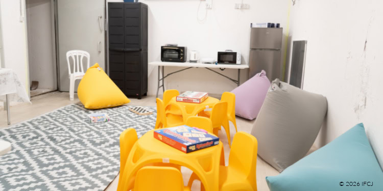 The image shows a cozy indoor space designed for children in shelters along the conflict line in the North, featuring bright cushions, small tables, and a welcoming environment to provide comfort and safety.