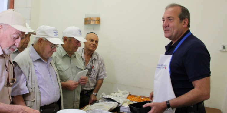 Rabbi Eckstein passing out food to a group of elderly men.