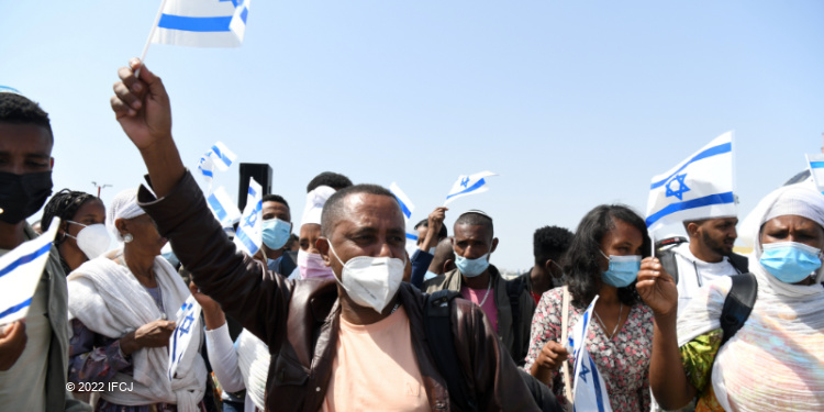 Ethiopians holding up Israeli flags while making Aliyah.