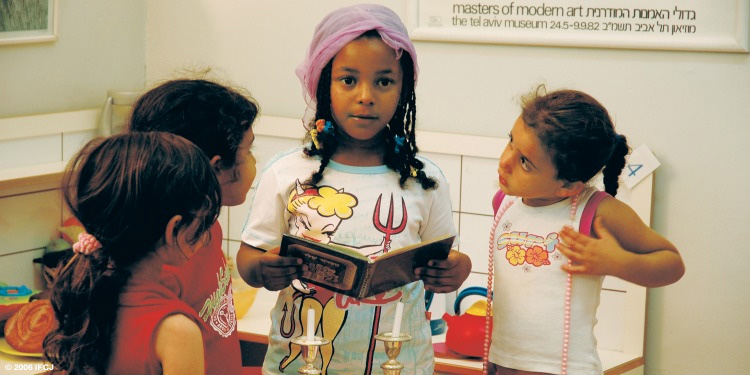 Four Ethiopian girls standing together while going through a children's book.