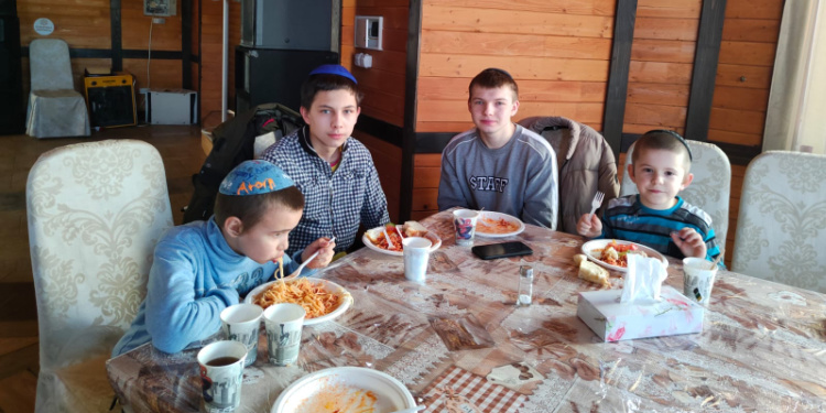 Four evacuated children sharing a meal together before Shabbat