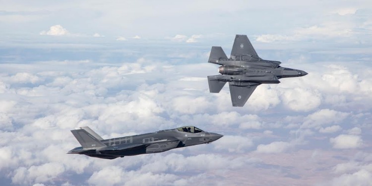 Two fighter jets flying in a cloudy sky.