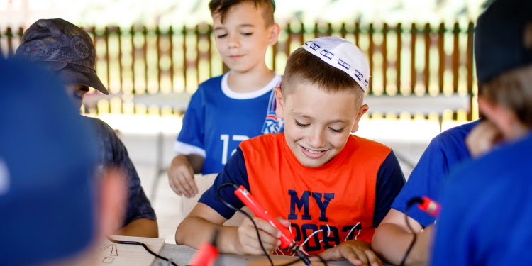 Several young boys drawing on pieces of wood.