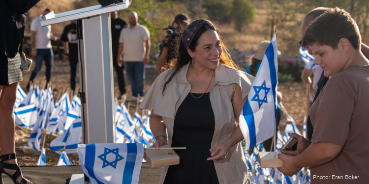 People gathering outdoors with Israeli flags during a memorial event for October 7 in Israel.