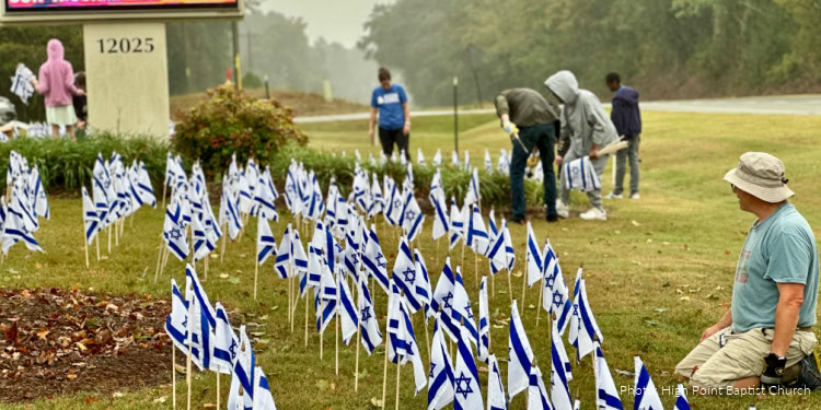 People planting Israeli flags during the Third Annual Flags of Fellowship Campaign event, promoting solidarity and support for Israel.
