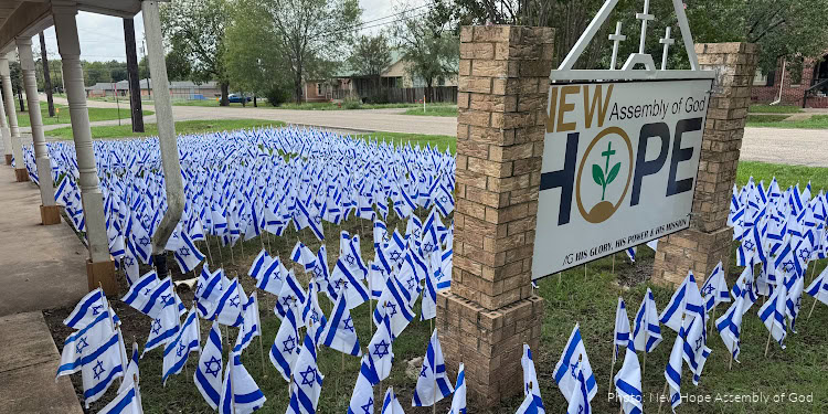 A large outdoor display of numerous Israeli flags surrounding a Hope Assembly of God sign, symbolizing faith and national pride.