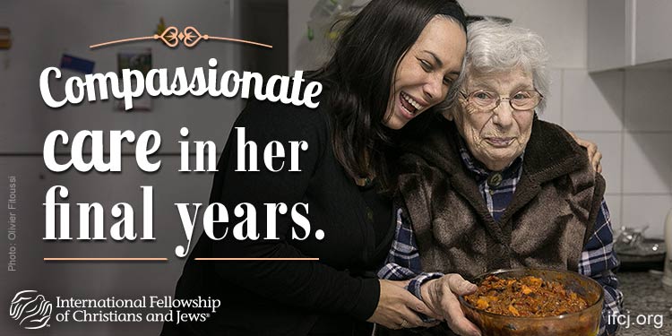 Yael Eckstein and Ana, an IFCJ recipient embracing in a kitchen while holding a bowl of food.