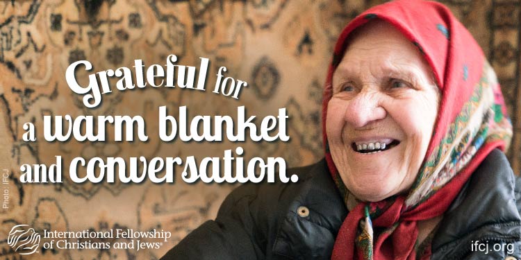 IFCJ promotion featuring a smiling elderly woman with the text: Grateful for a warm blanket and conversation.