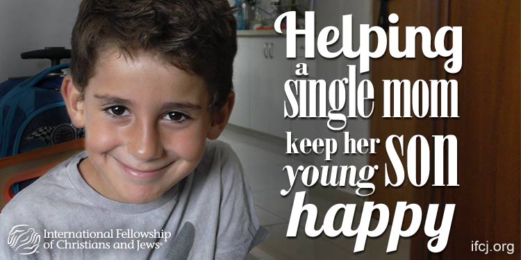 Yonatan, a young IFCJ recipient smiling while sitting at his dining room table.
