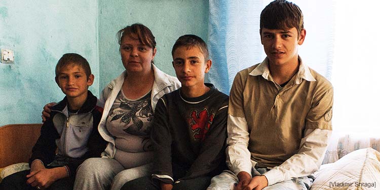 A family of four sitting on a bed together.