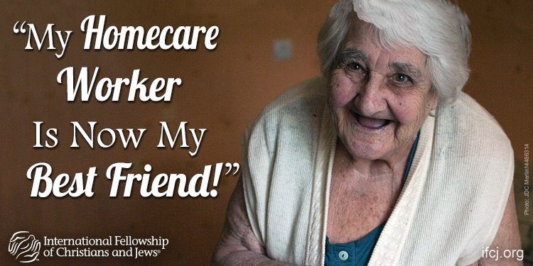 Maya, an elderly Jewish woman smiling up in a white sweater featured in an IFCJ promotion.