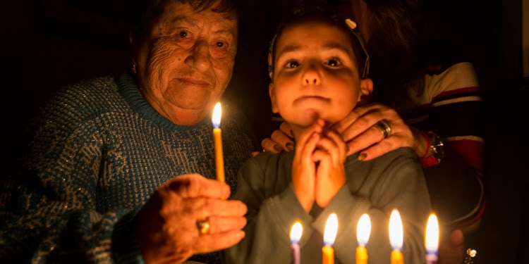 Young boy and an elderly Jewish woman lighting candles.