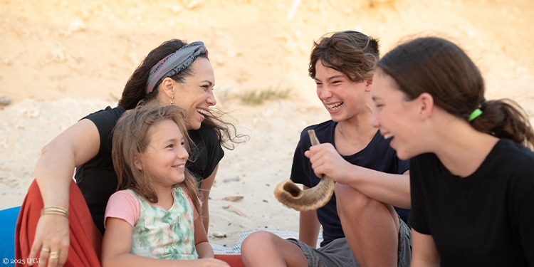 Yael and her children sitting on the beach with a shofar during Passover
