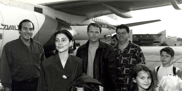 Black and white image of a family getting off a plane with Rabbi Eckstein at their side.