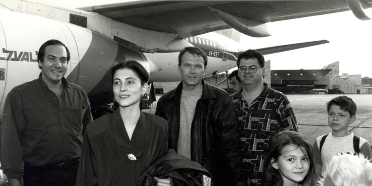 Black and white image of Rabbi Eckstein standing with a family who just made Aliyah.
