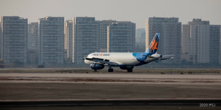 Flydubai commercial airplane taxiing on runway with cityscape in background.