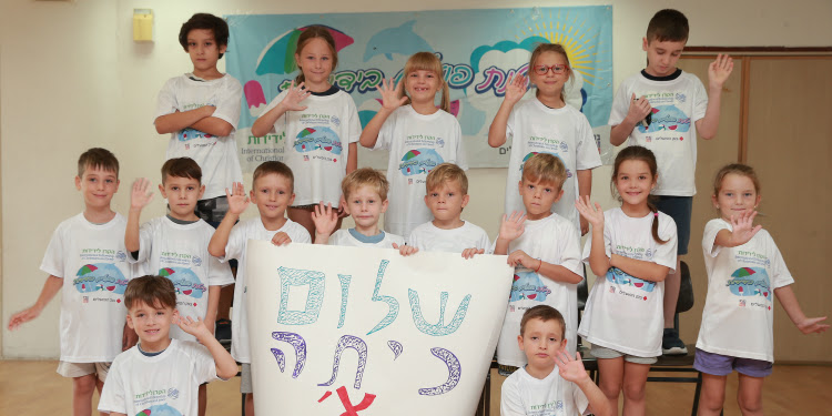 Several children wearing IFCJ shirts holding a sign they made.