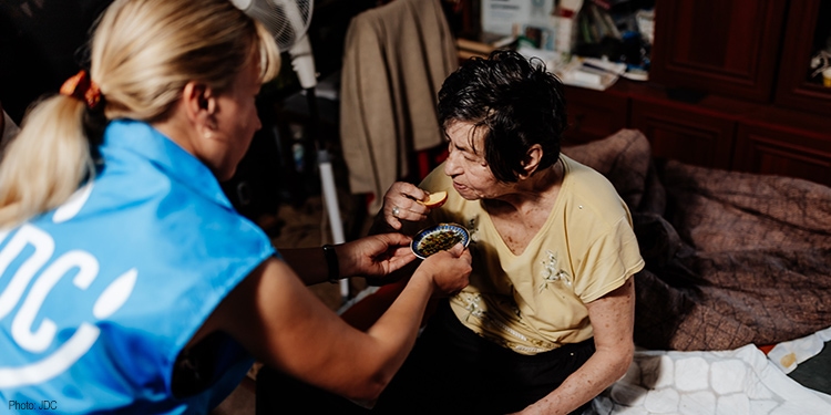 Fellowship volunteer feeding elderly woman