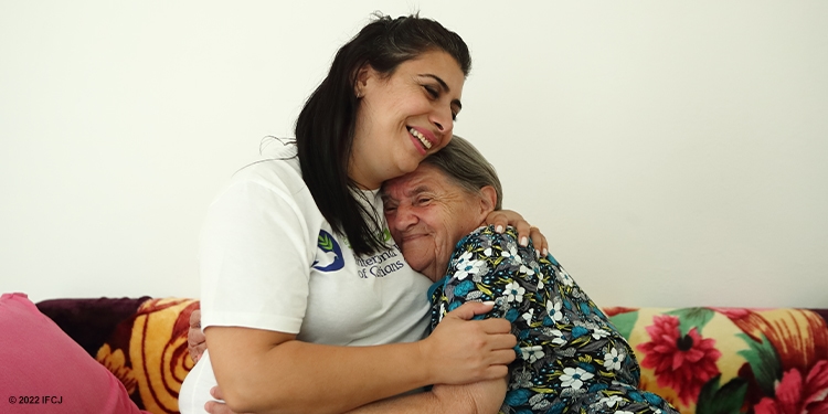 Fellowship volunteer hugging elderly woman