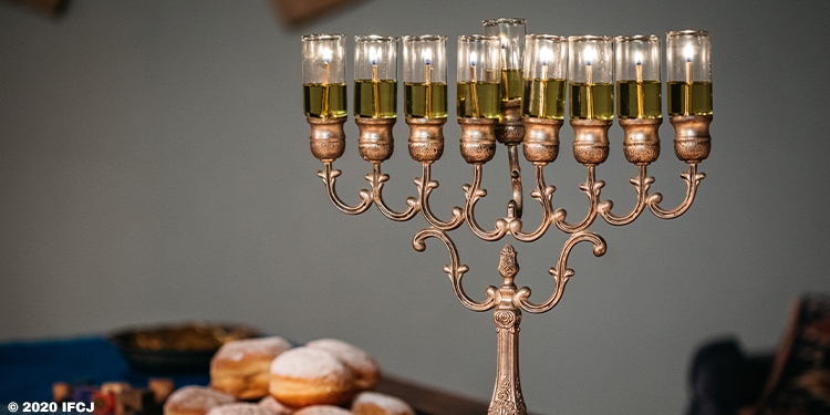 Gold and bronze menorah with lit candles.