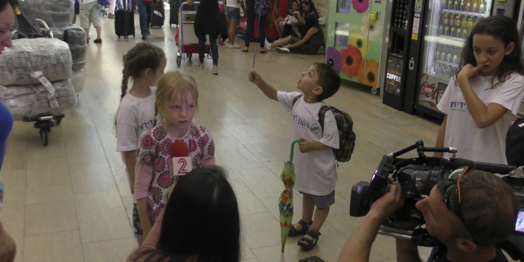 Several young kids wearing IFCJ branded shirts standing for school.