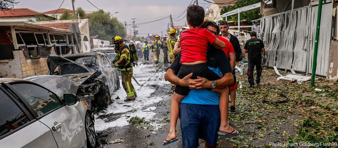 Israeli man carries child away from destruction in Southern Israel