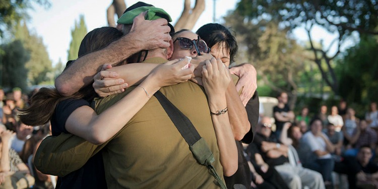 Soldier hugging three women with his back faced to the camera.