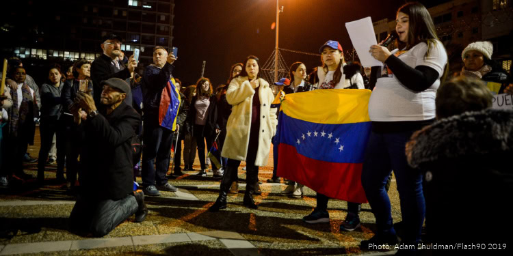 Israeli rescue volunteers participate in a gathering in Venezuela, holding a Venezuelan flag and engaging with local community members during a humanitarian mission.